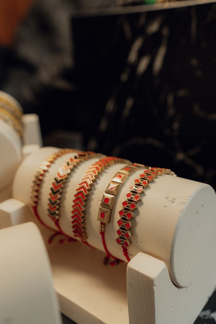 A close-up of stylish gold and red bracelets elegantly displayed on a white jewelry stand.